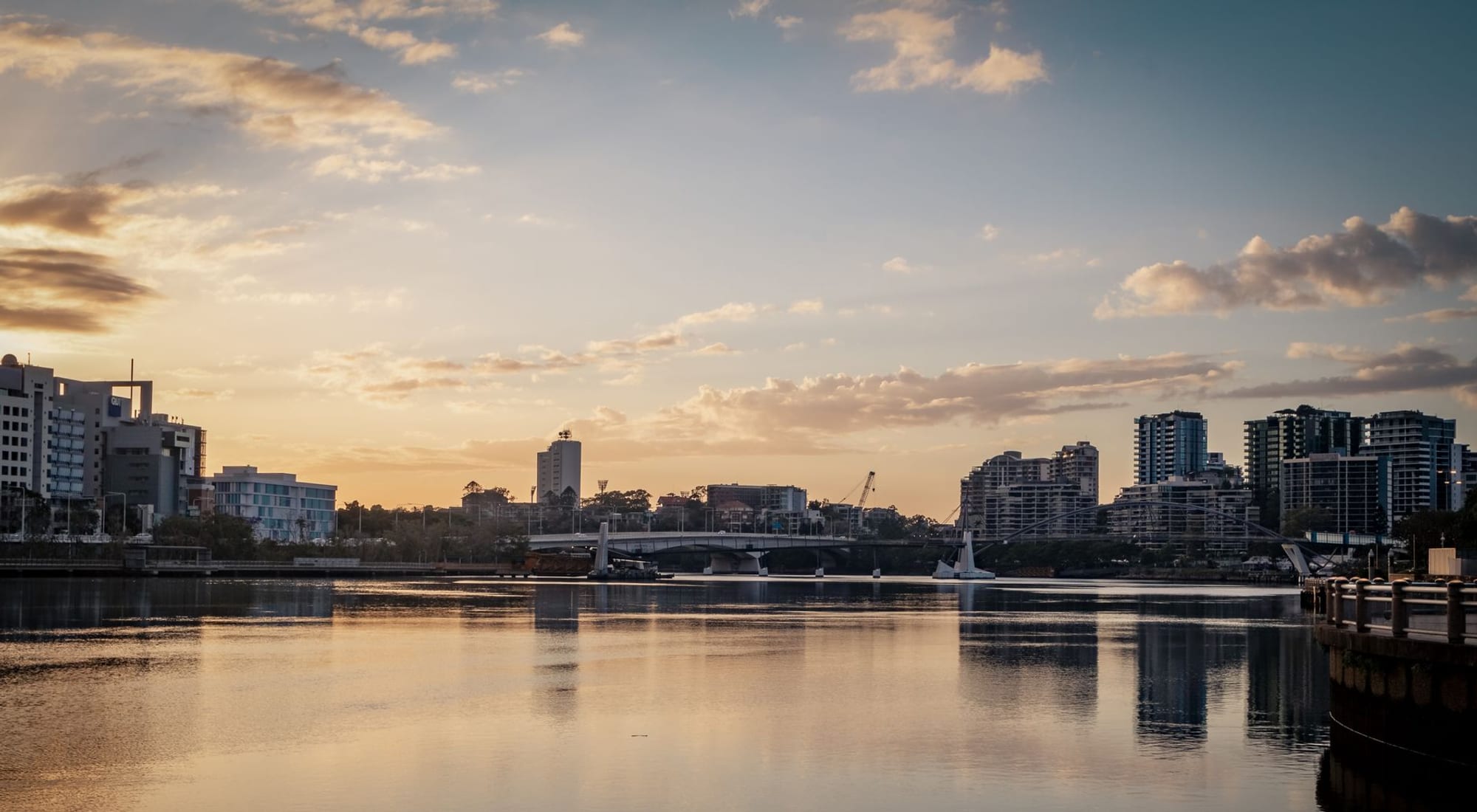 A city skyline reflected on a calm river at dawn